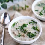 two bowls of sausage and kale soup garnished with pepper