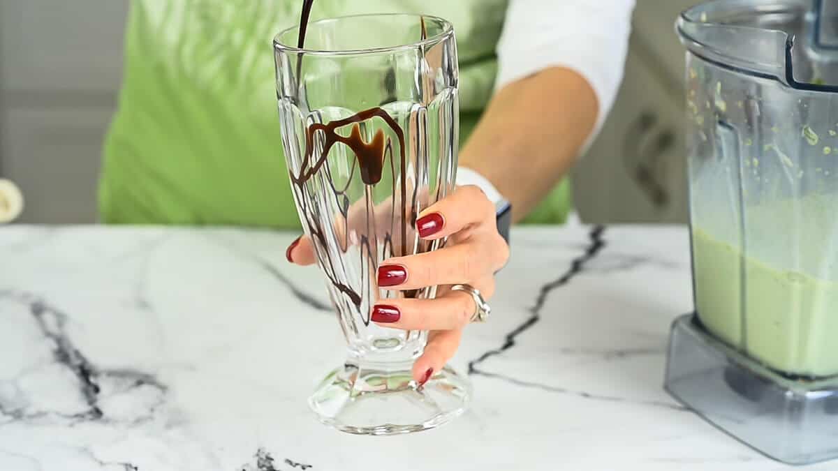 chocolate sauce being poured into a shake glass