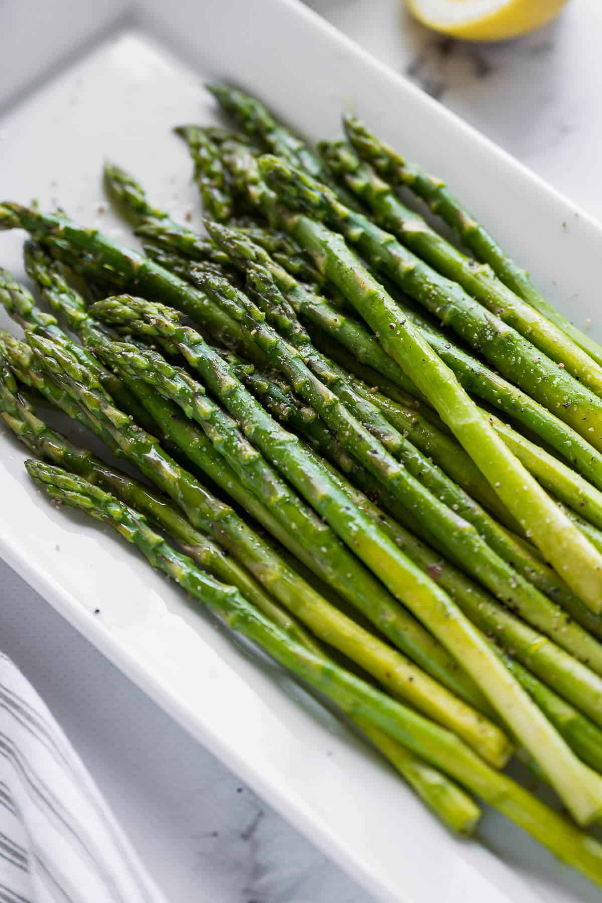 platter of asparagus garnished with oil and lemon