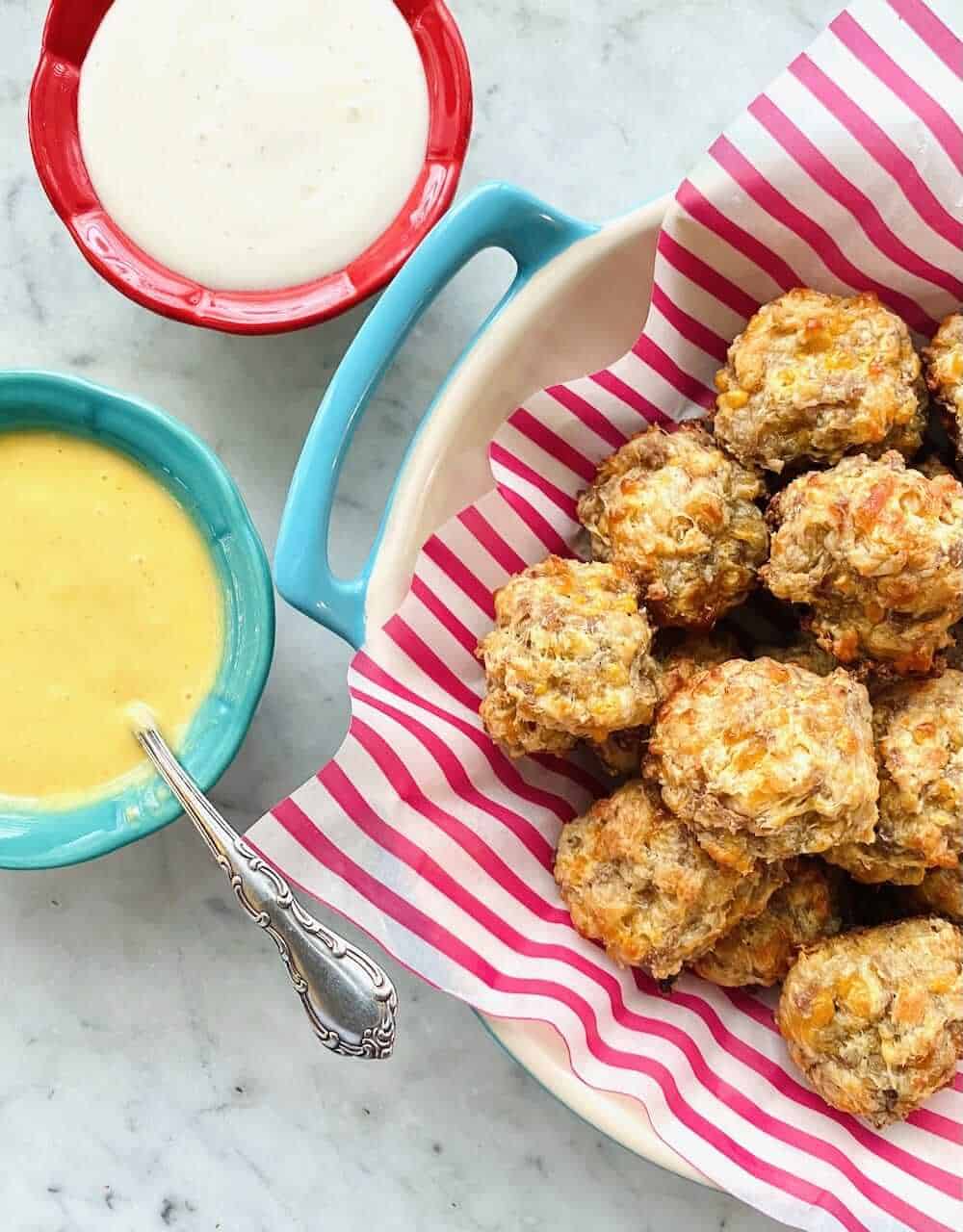 sausage balls in a dish served along side a cheese dip and a ranch dip