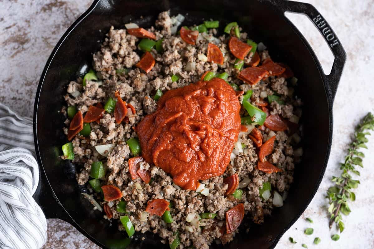 sausage, pepperoni, green pepper, onion and pizza sauce in a cast iron skillet