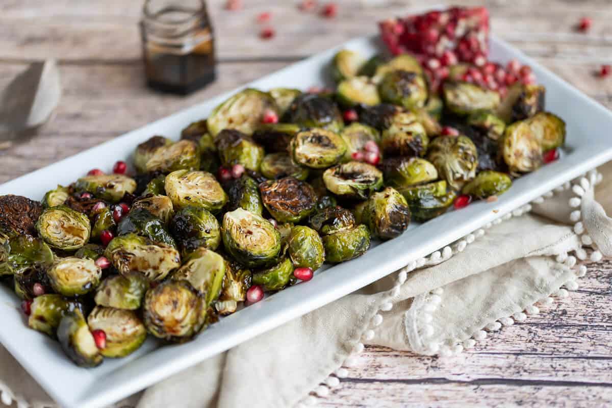 Platter of roasted brussels sprouts with balsamic reduction and pomegranate arils.