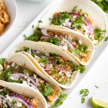platter of soft tacos with chicken tinga, red onion, cheese, and cilantro