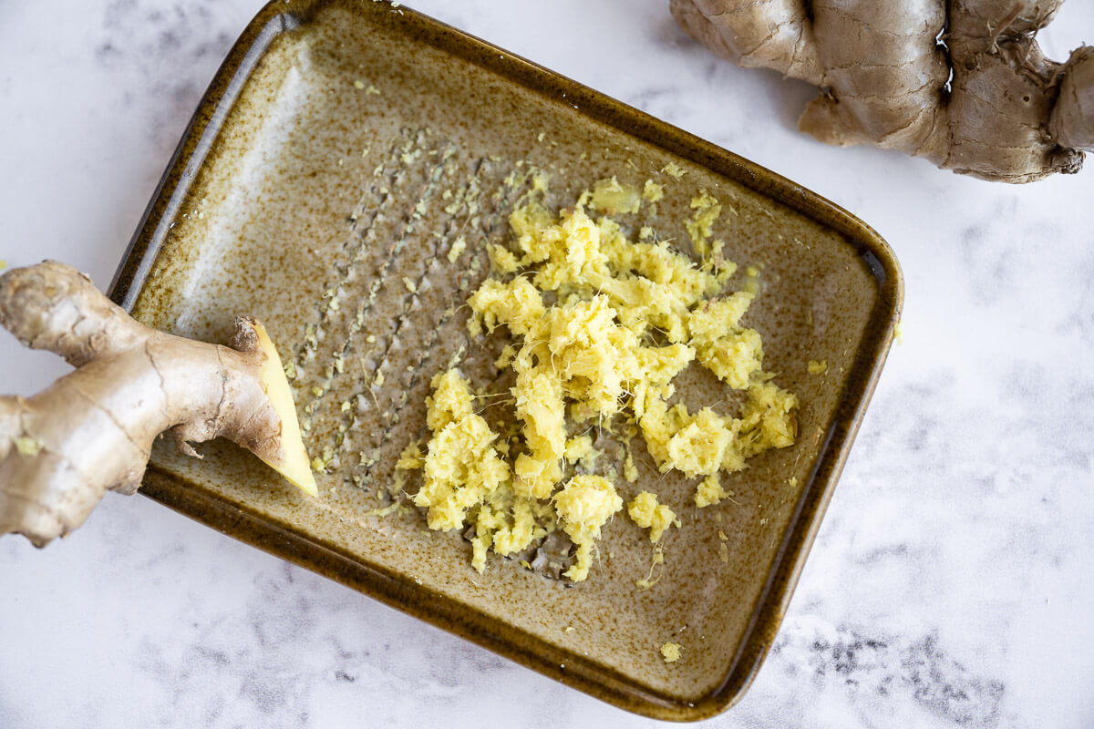grated fresh ginger on a ceramic ginger grater