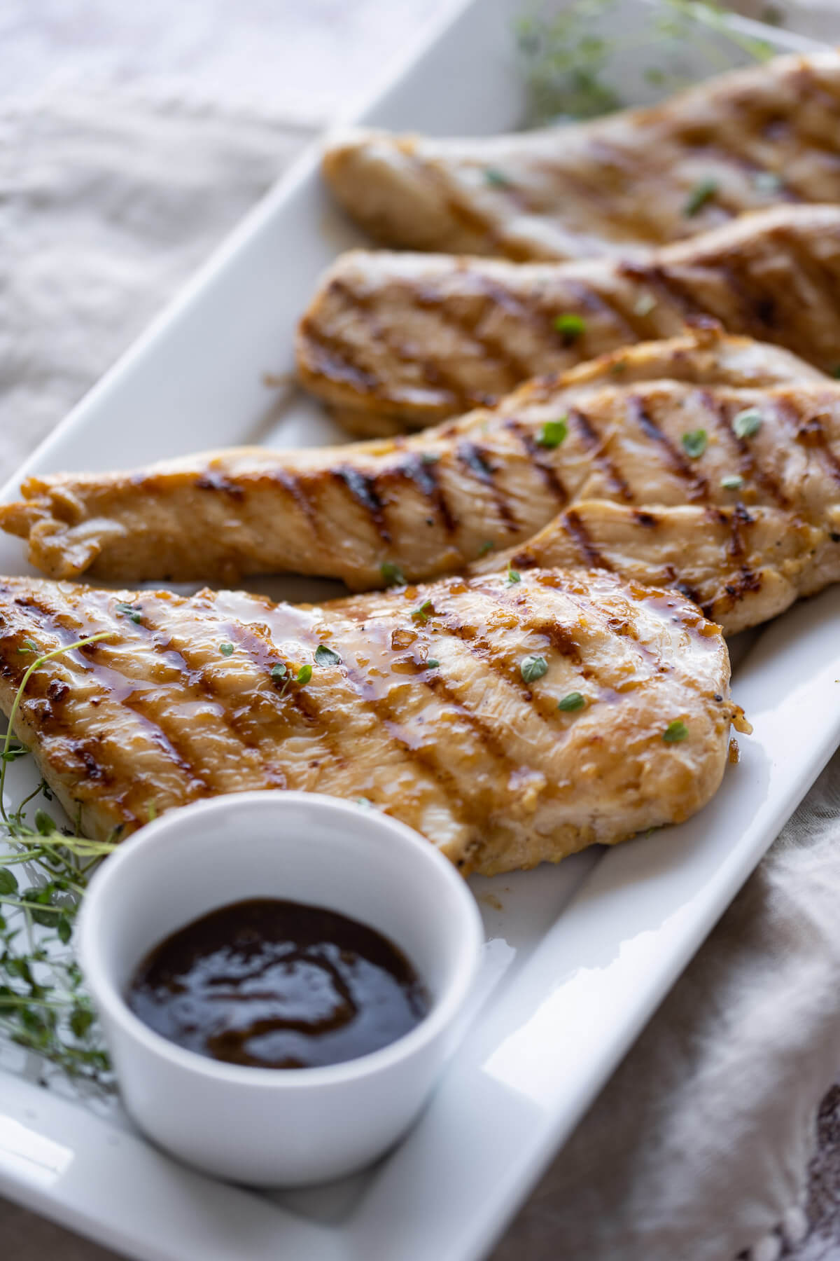 grilled chicken breasts on a white rectangle platter