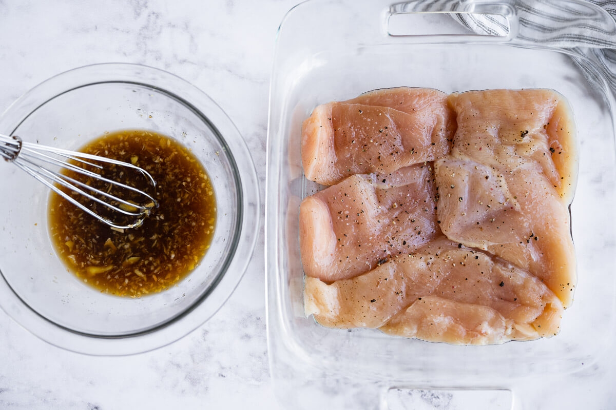 homemade teriyaki sauce in a bowl next to seasoned raw chicken breasts
