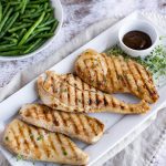 grilled chicken with teriyaki sauce on a white platter, served with green beans and white rice