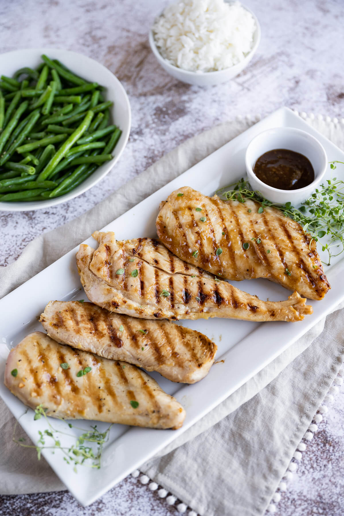 grilled chicken with teriyaki sauce on a white platter, served with green beans and white rice