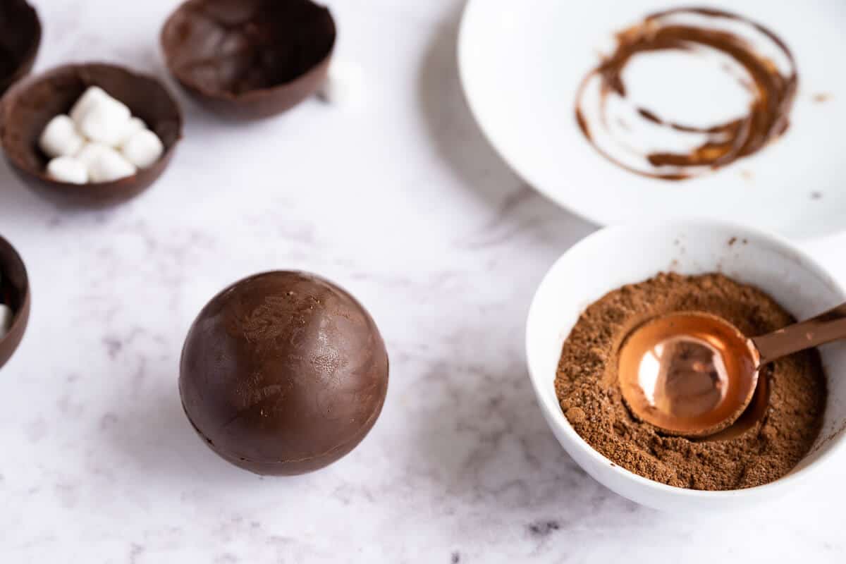sealed hot cocoa bomb next to hot cocoa mix and yet to be sealed hot chocolate bombs