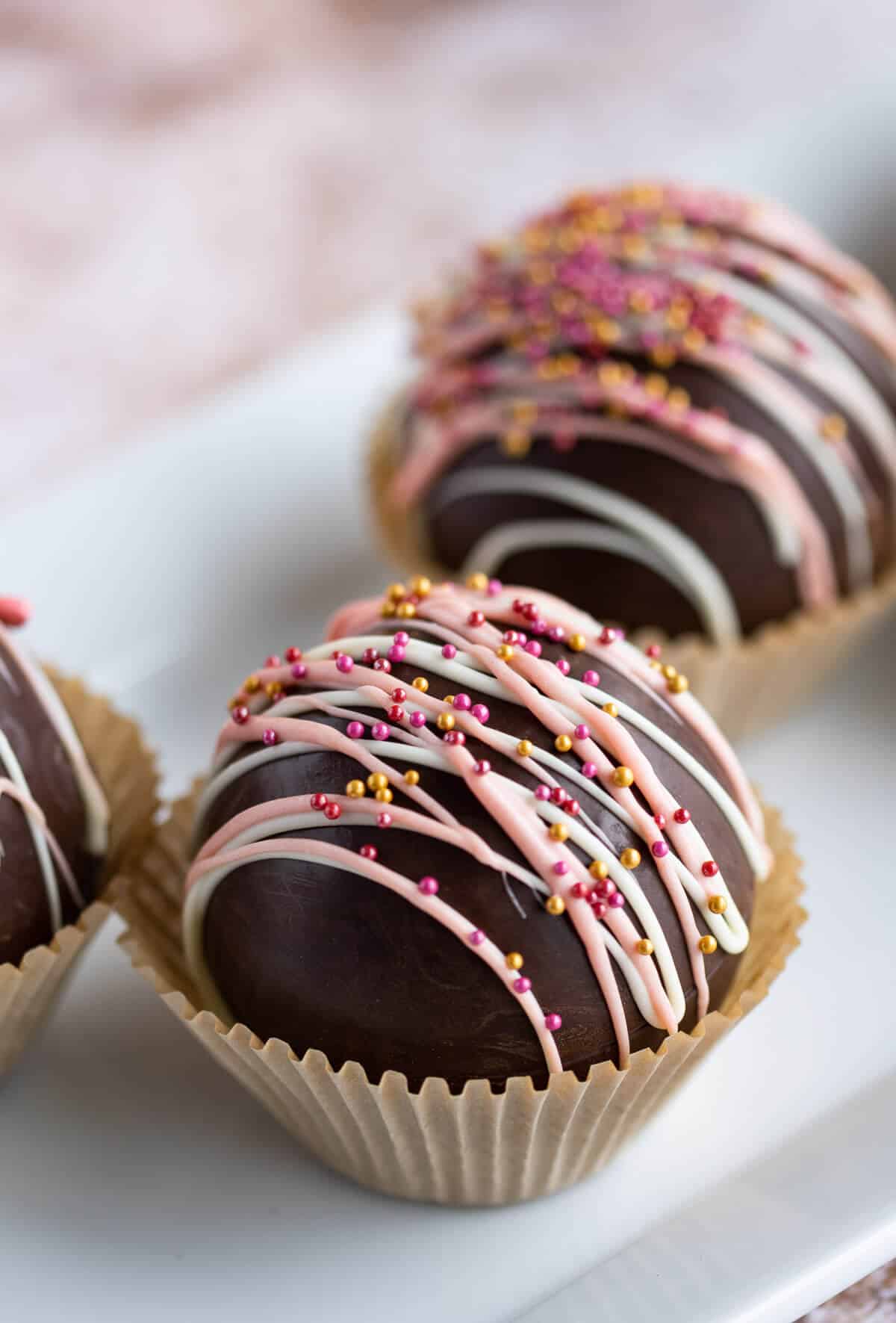 Hot cocoa bomb drizzled with white chocolate and pink and gold sprinkles