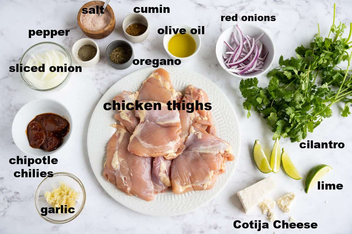 ingredients for chicken tinga- boneless chicken thighs, onion, chipotle peppers, garlic, salt, pepper, cumin, oregano, red onions, cilantro, lime, cheese