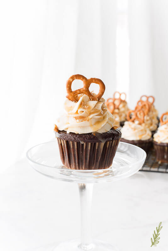 chocolate cupcake topped with irish cream frosting and a pretzel in a champagne glass