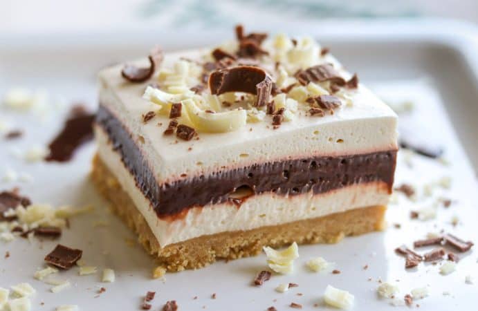 a piece of Irish Cream Dream bars, a layered dessert, on a plate garnished with white and milk chocolate.