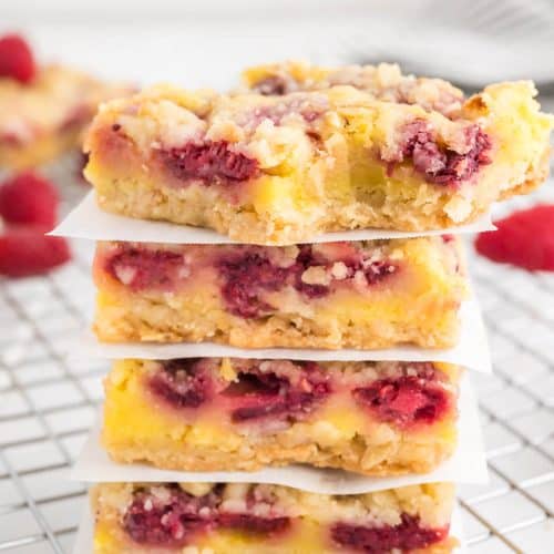 4 stacked raspberry bars with sheets of wax paper between them.