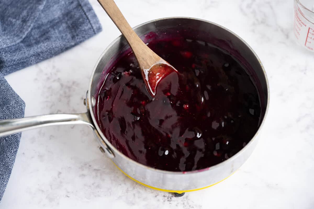 blueberry pie filling in a sauce pan showing the thick and glossy texture