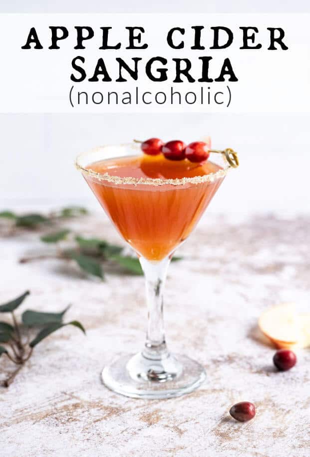apple cider mocktail in a martini glass rimmed in sugar and garnished with fresh cranberries via @artfrommytable