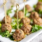 Oven baked seasoned meatballs without sauce on a platter garnished with fresh parsley