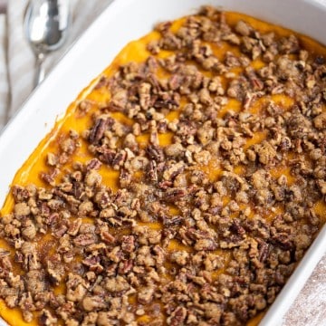 Whipped Sweet Potato Casserole with a Pecan Praline Crunch topping baked in a white casserole dish.