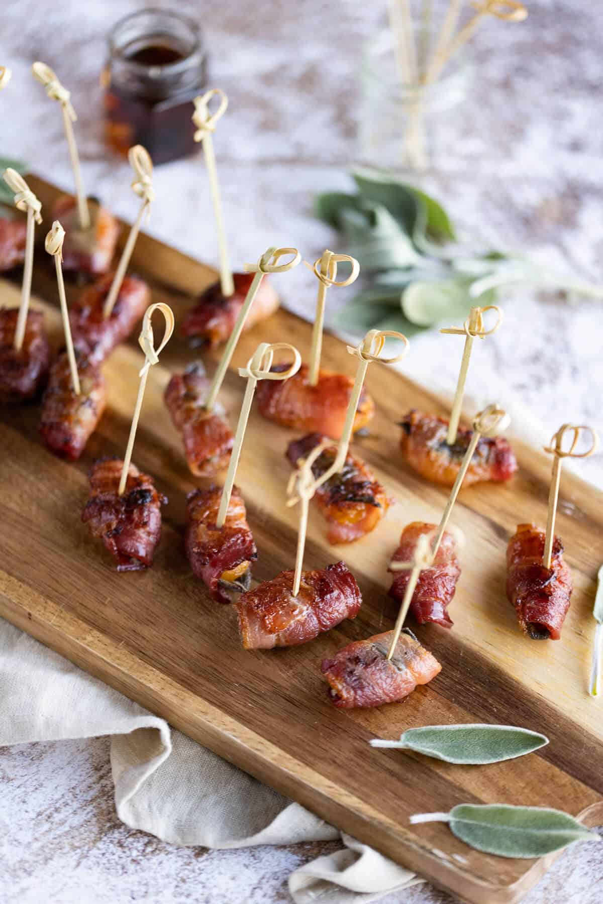 Bacon wrapped apricots with toothpicks for serving on a wooden serving board.