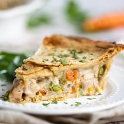 Slice of homemade turkey pot pie on a white plate garnished with fresh chopped parsley