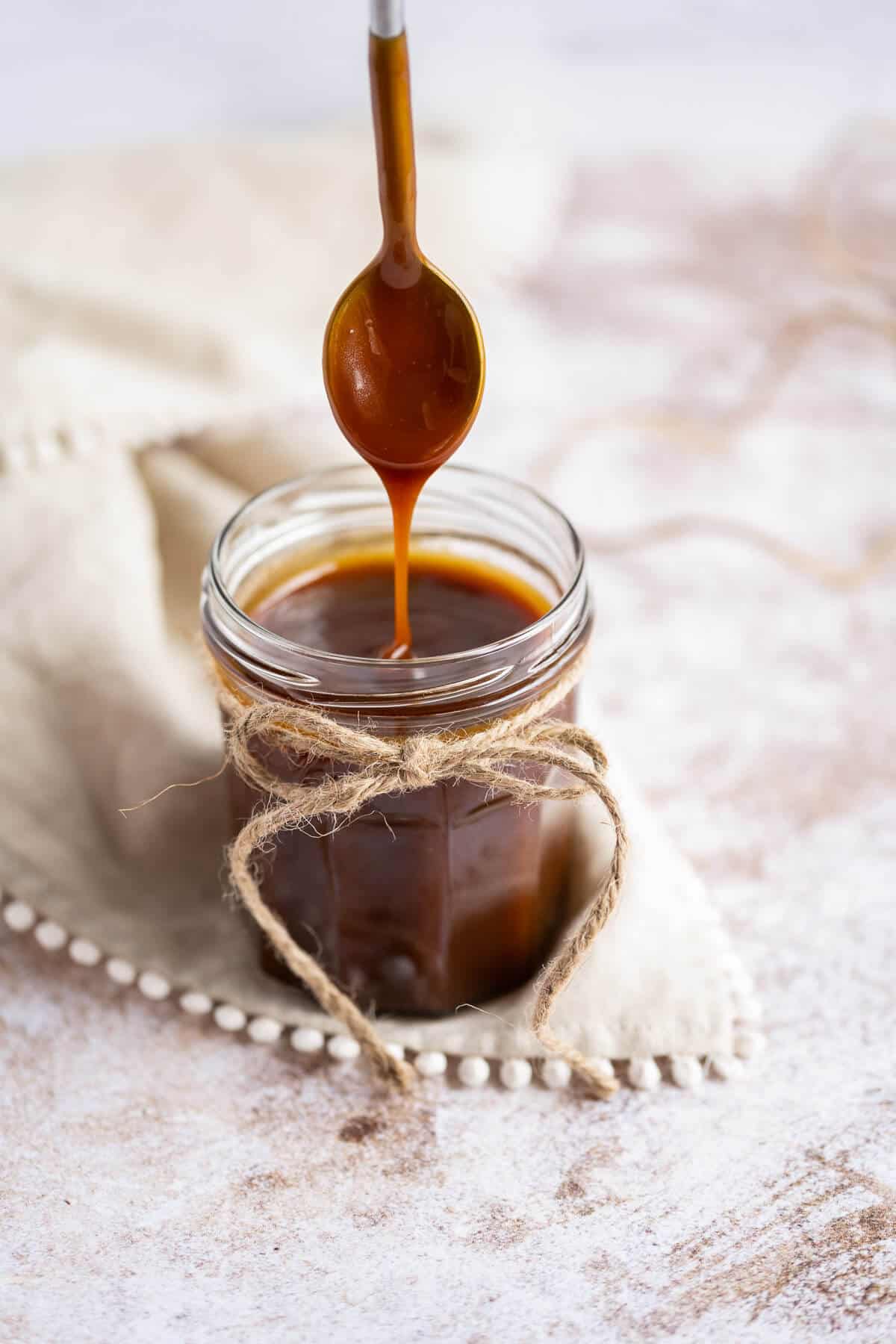 caramel sauce dripping from the spoon into its jar.