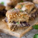 Baked sliders stuffed with roast beef, cheese, and caramelized onions, topped with fresh parsley.