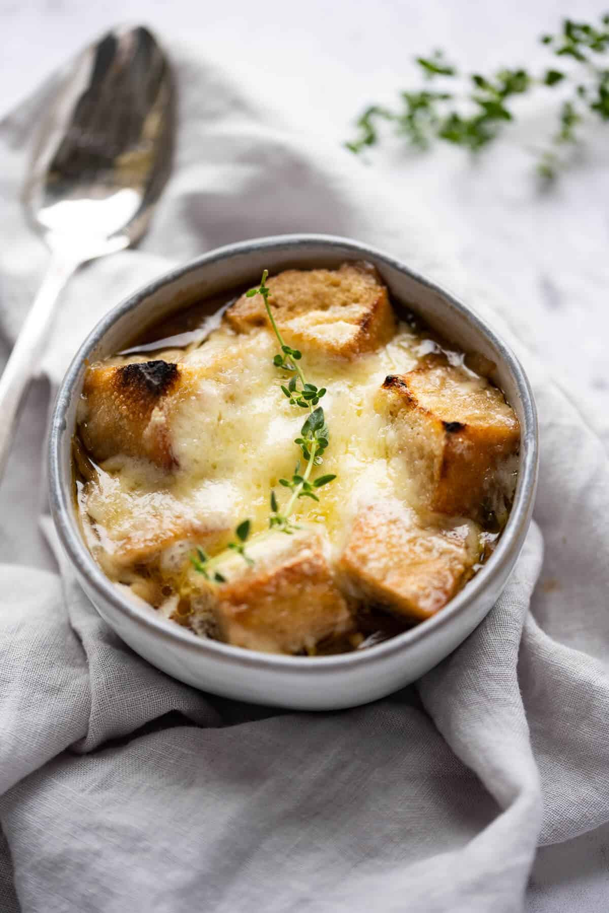 Gray bowl of Panera style French Onion Soup garnished with fresh thyme.
