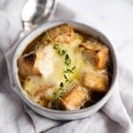 Gray bowl of Panera style French Onion Soup garnished with fresh thyme.