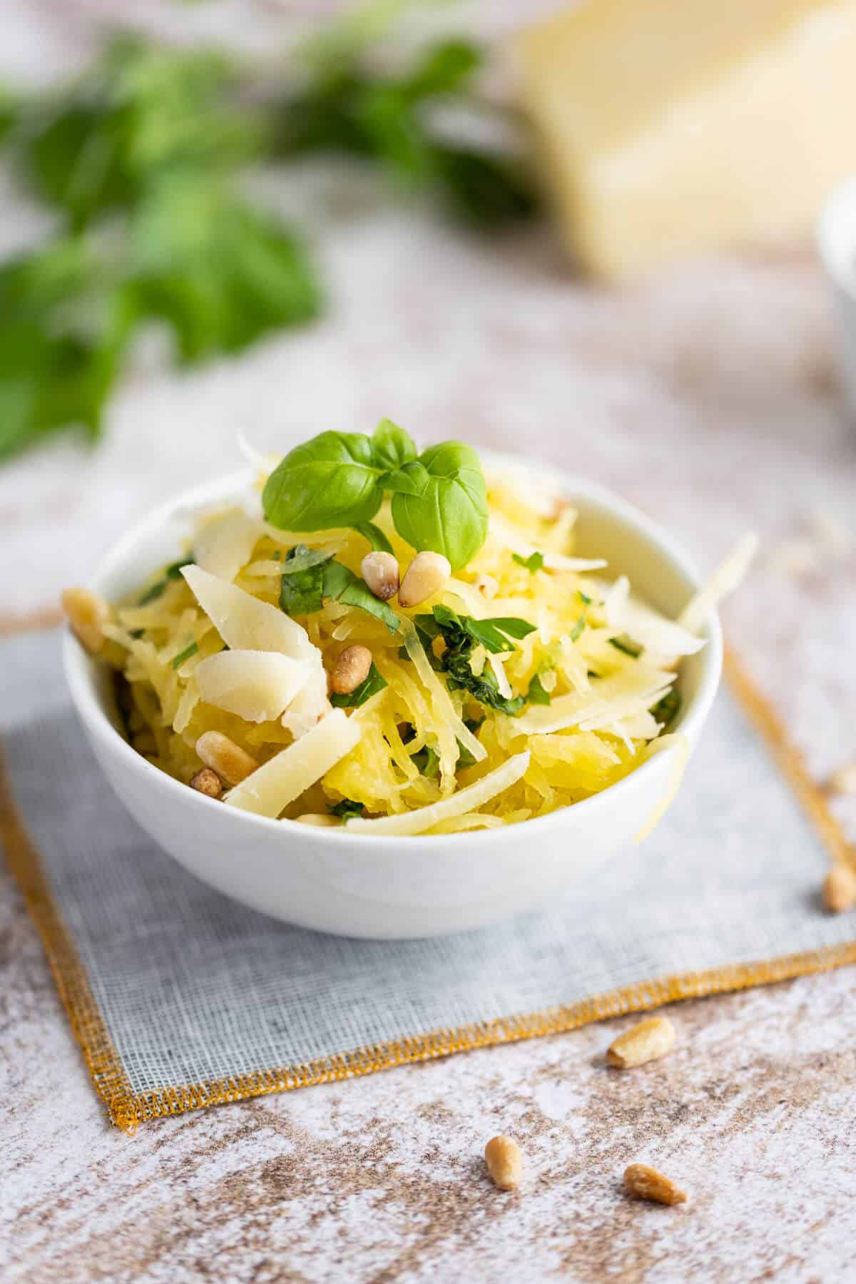 Cooked spaghetti squash in a white bowl with garlic, parmesan and fresh herbs.