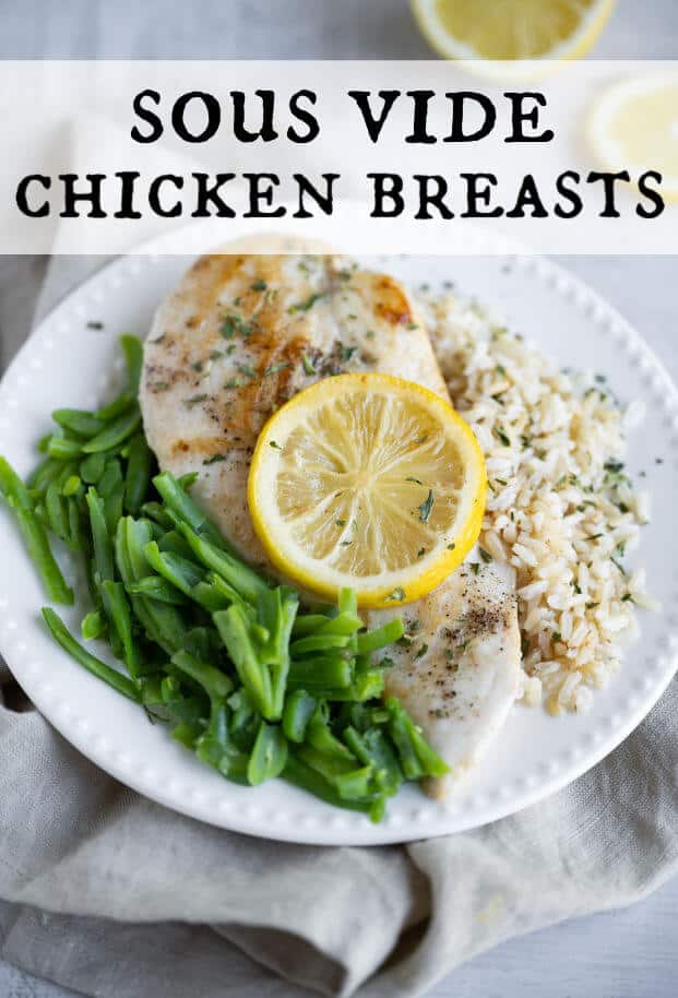 Chicken breast, cooked sous vide method, on a plate with green beans and rice. Chicken is garnished with a lemon slice. via @artfrommytable