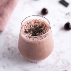 Dark Cherry Smoothie with chocolate in a stemless wine glass garnished with shaved dark chocolate.