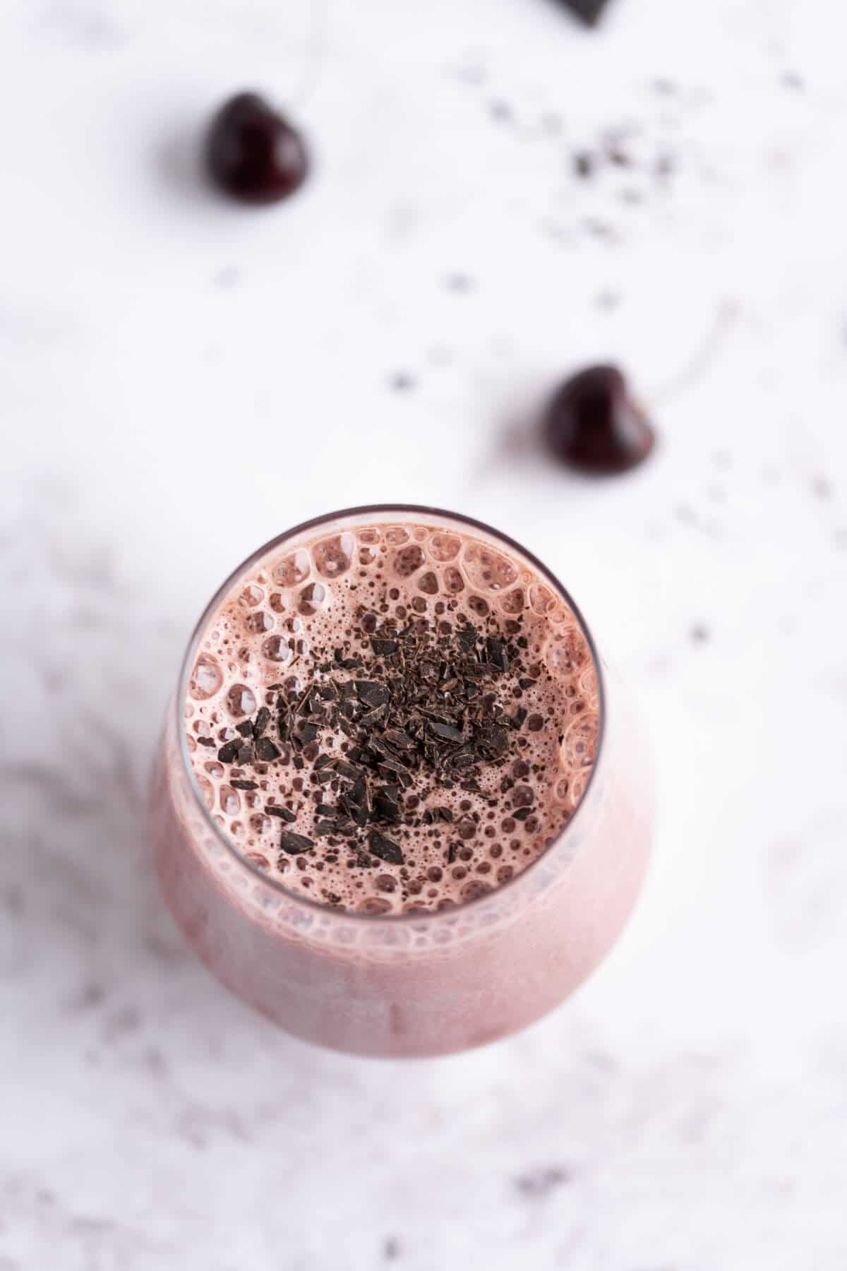 Dark Cherry Smoothie with chocolate in a stemless wine glass garnished with shaved dark chocolate.