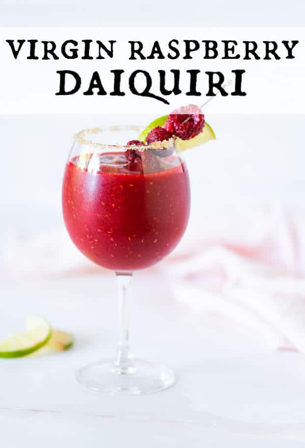 Frozen Raspberry Daiquiri Mocktail in a stemmed glass rimmed with sugar and garnished with fresh raspberries and lime wedge on a cocktail pick. via @artfrommytable