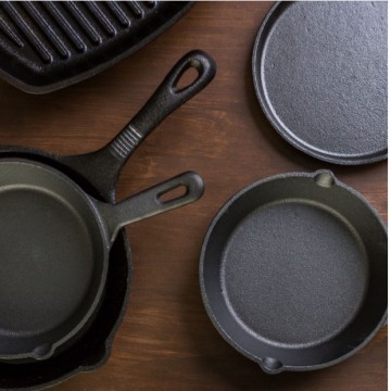 different sizes and types of cast iron pans on a wood countertop