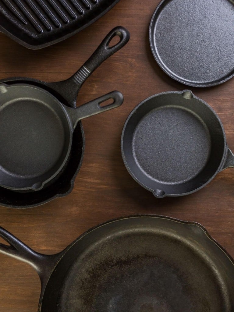 several cast iron skillets in different sizes. some have handles, some don't. One is a grill pan.