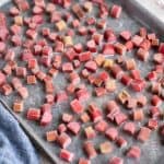 Frozen rhubarb in pieces on a rimmed baking sheet.