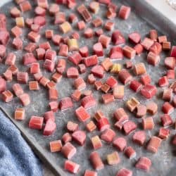 Frozen rhubarb in pieces on a rimmed baking sheet.