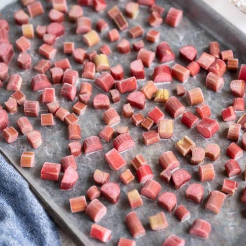 Frozen rhubarb in pieces on a rimmed baking sheet.