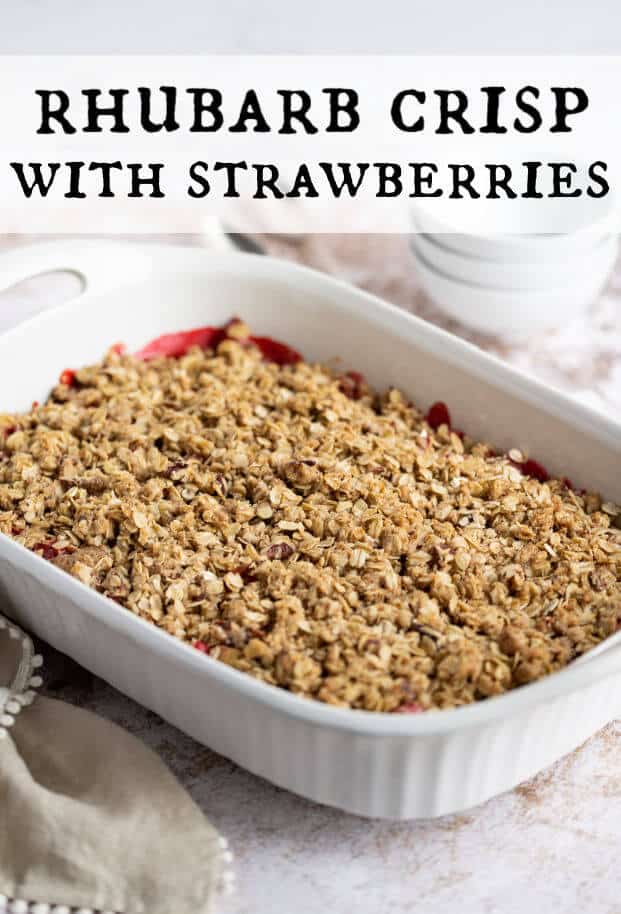 Just baked Rhubarb Strawberry Crisp in a white casserole dish with bowls for serving alongside. via @artfrommytable