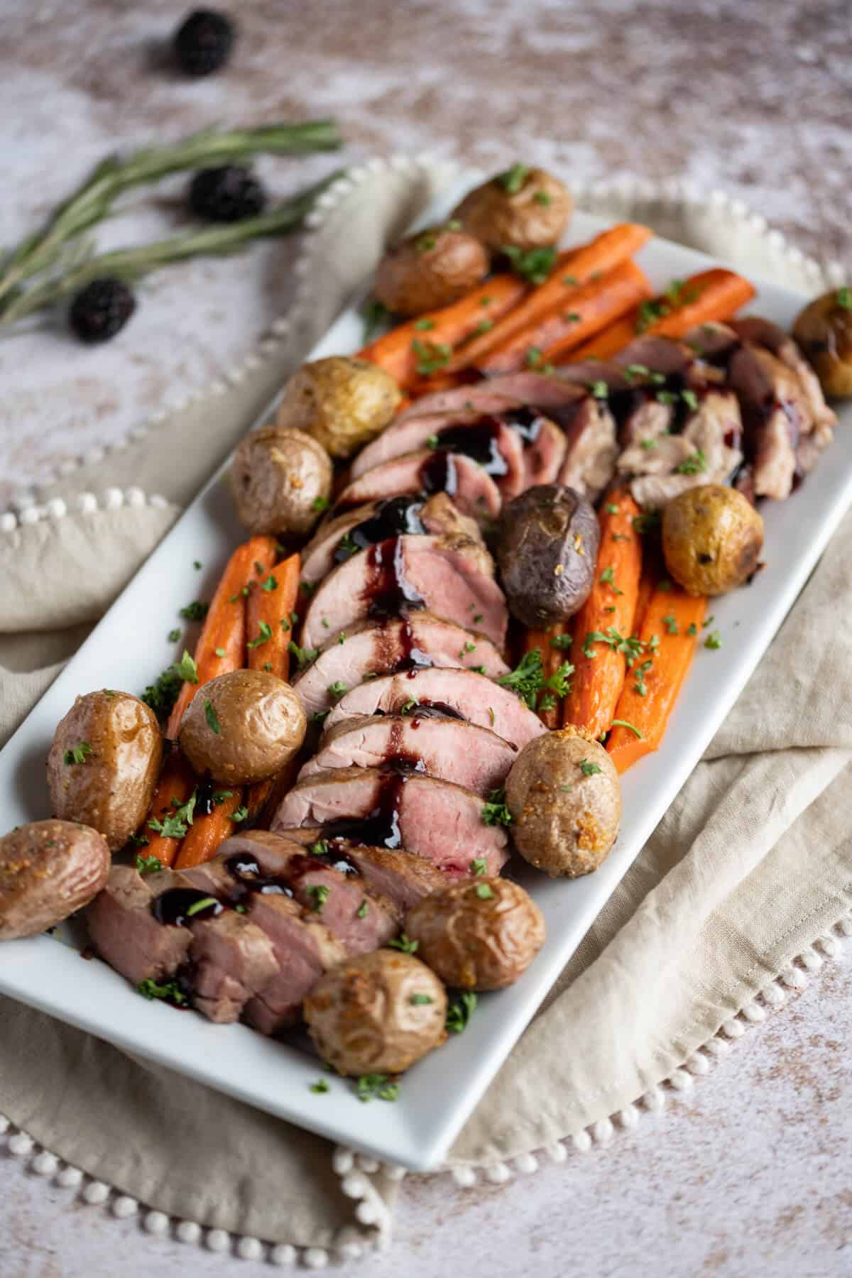 Rectangle Platter with sliced pork tenderloin laid out in an S pattern surrounded by roasted carrots and potatoes.