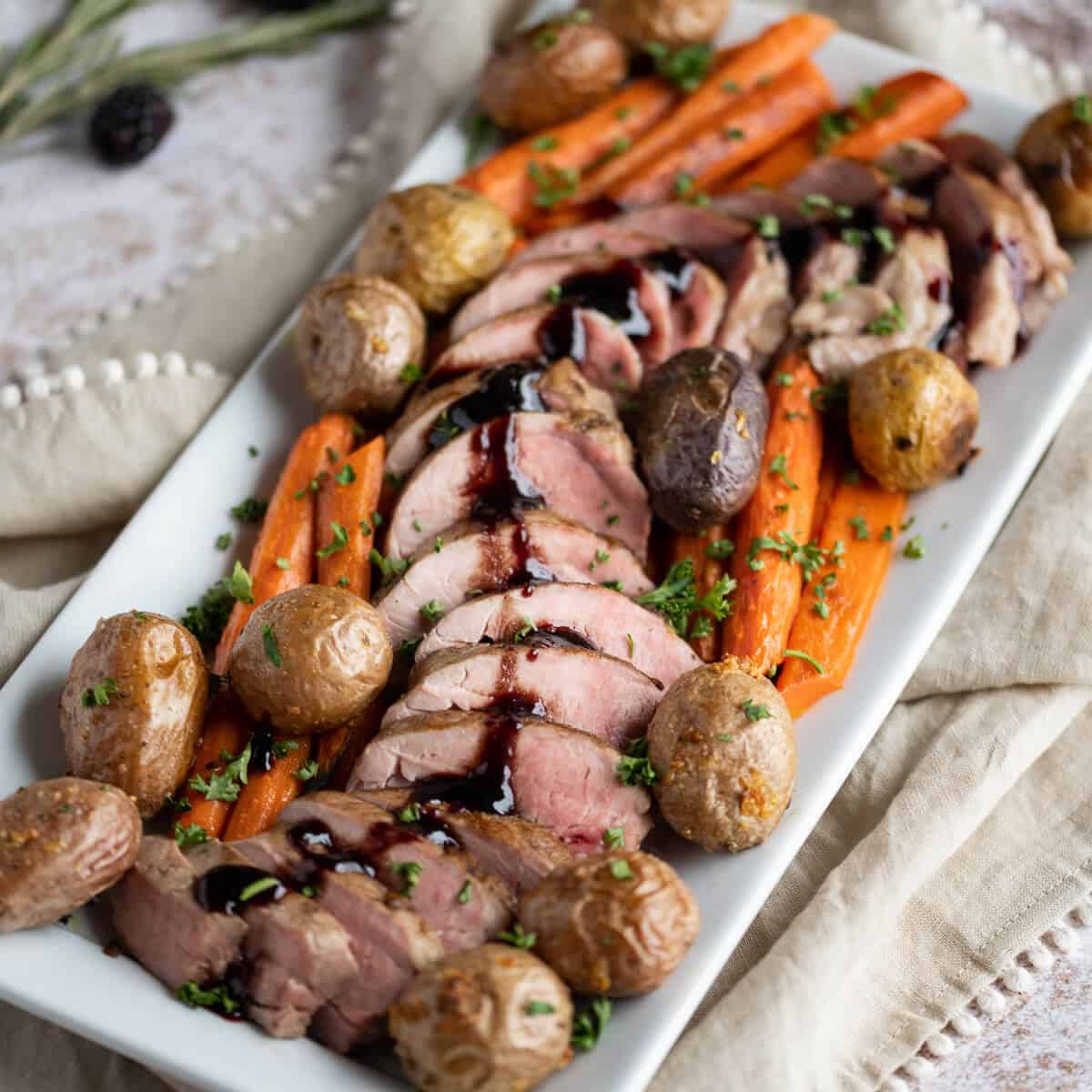 Rectangle Platter with sliced pork tenderloin laid out in an S pattern surrounded by roasted carrots and potatoes.