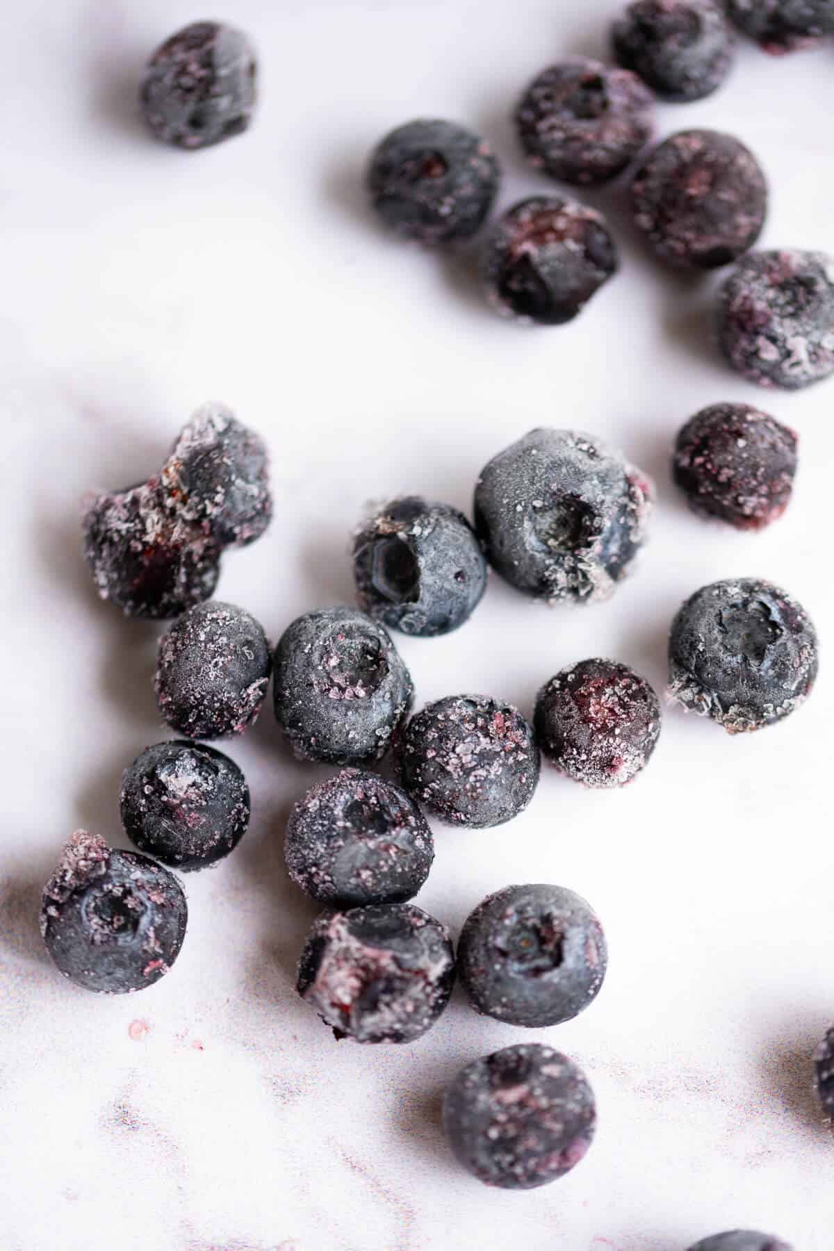 A group of frozen blueberries on a marble countertop.