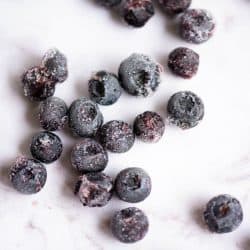 A group of frozen blueberries on a marble countertop.