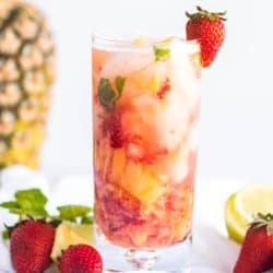 Strawberry Pineapple Mojito in a tall clear glass with ice, garnished with a fresh strawberry.