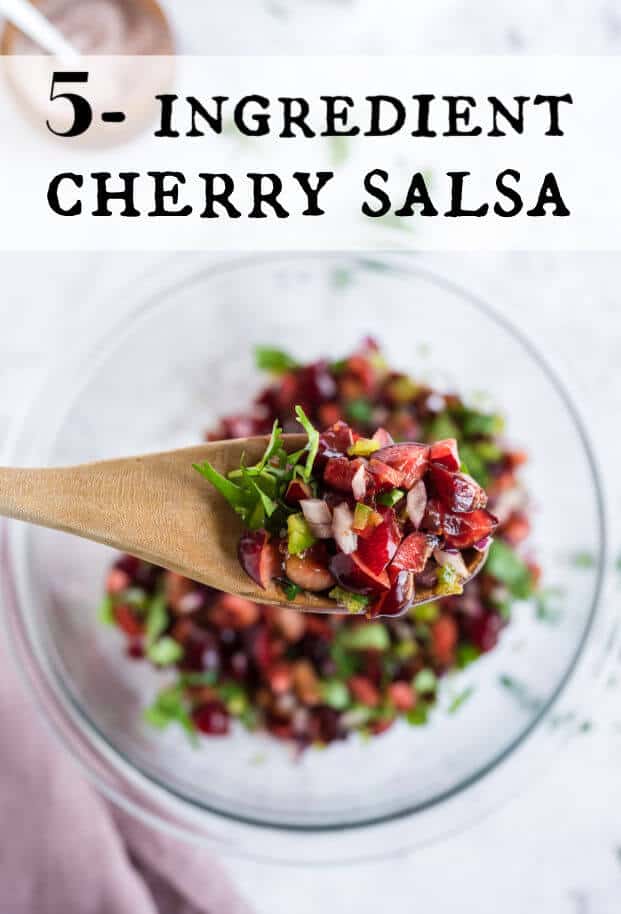 Cherry salsa on a wooden spoon being held above a bowl of salsa. via @artfrommytable
