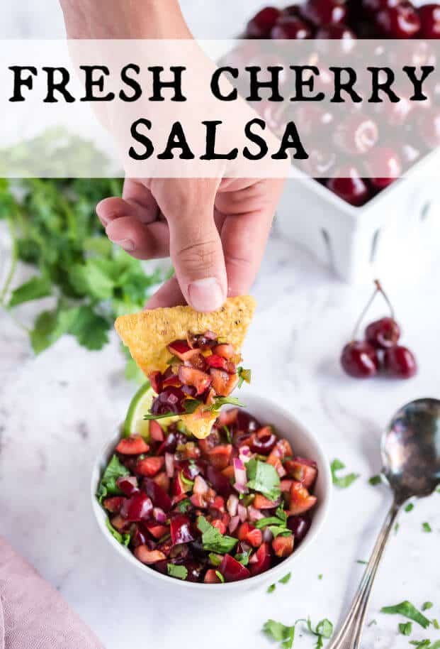 Hand holding a chip with a mound of cherry salsa on it. via @artfrommytable