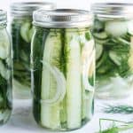 Jars of overnight pickles, fresh dill in the foreground.