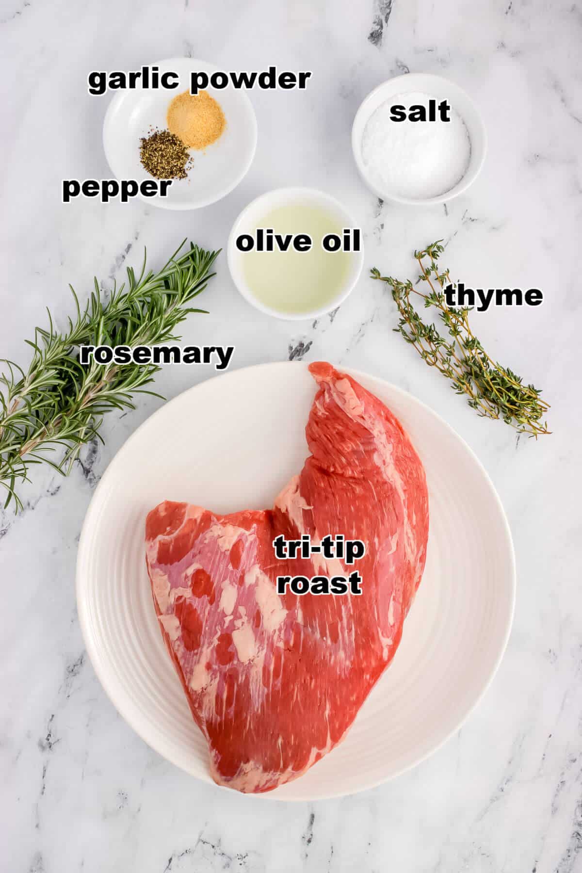 Ingredients needed to make sous vide tri-tip roast. Tri-tip, salt, pepper, garlic powder, olive oil, rosemary, and thyme.