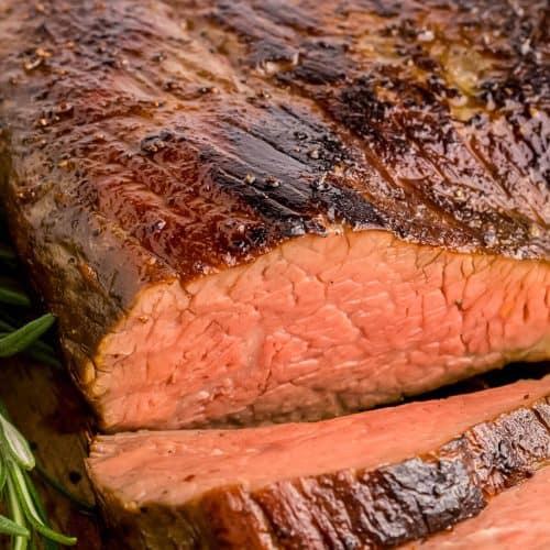 Sous vide Tri-tip roast on a cutting board, sliced into. Top is seared nicely and a few slices are layed down in front of the roast.