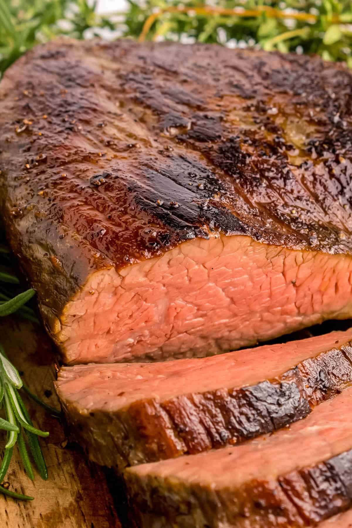 Sous vide Tri-tip roast on a cutting board, sliced into. Top is seared nicely and a few slices are layed down in front of the roast.